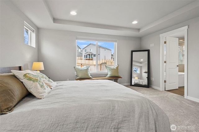 carpeted bedroom with recessed lighting, a raised ceiling, connected bathroom, and baseboards