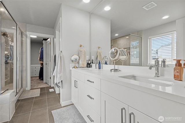 full bathroom featuring double vanity, visible vents, a stall shower, a sink, and tile patterned flooring