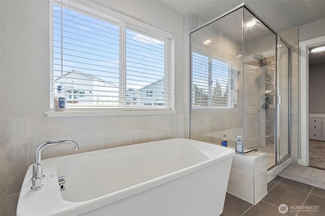 full bathroom with a freestanding bath, a stall shower, tile walls, and tile patterned floors