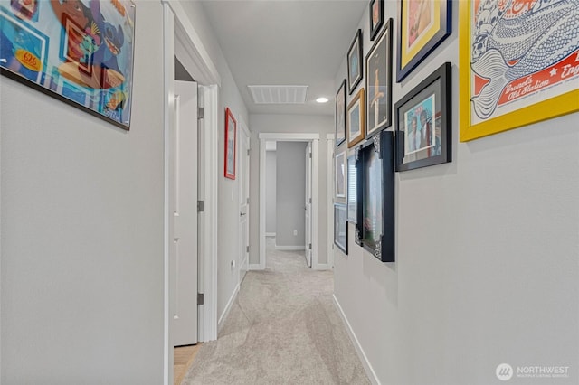 corridor with visible vents, light carpet, and baseboards