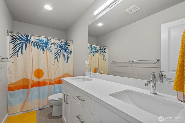 full bathroom with toilet, double vanity, visible vents, and a sink