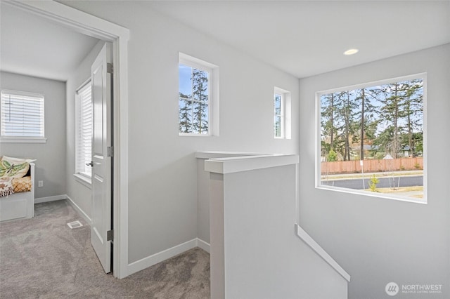 hallway featuring visible vents, carpet flooring, an upstairs landing, and baseboards