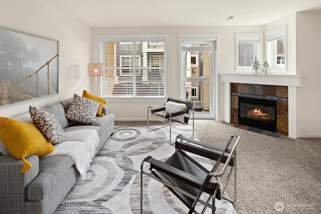 living room featuring visible vents, a fireplace, baseboards, and carpet