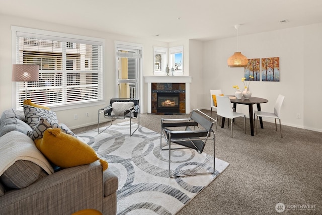 living room featuring baseboards, carpet floors, and a tile fireplace