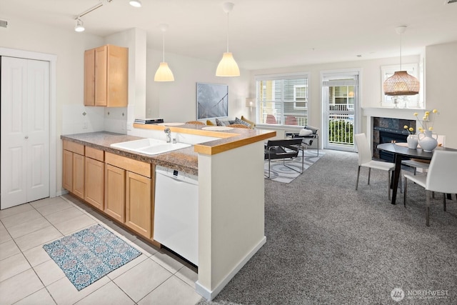 kitchen featuring light brown cabinets, open floor plan, dishwasher, a peninsula, and a sink