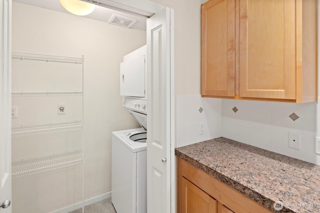 laundry area with visible vents, stacked washer and clothes dryer, and laundry area