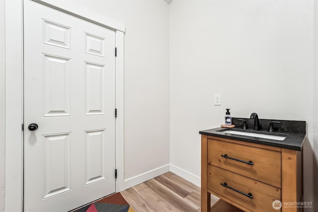 bathroom featuring baseboards, wood finished floors, and vanity