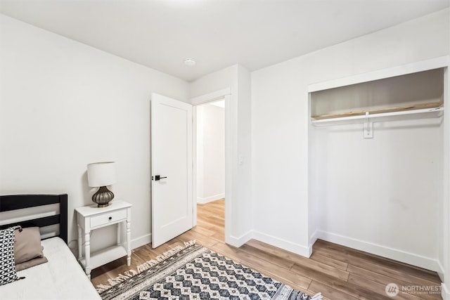 bedroom featuring a closet, baseboards, and wood finished floors