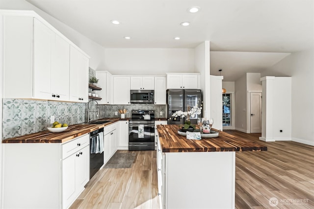 kitchen with butcher block countertops, a sink, white cabinets, appliances with stainless steel finishes, and a center island