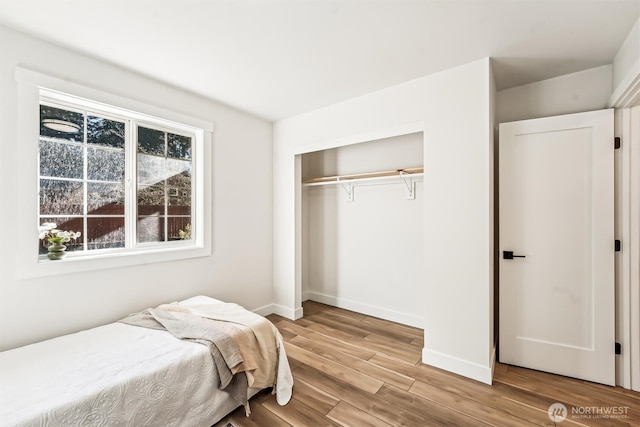 bedroom with a closet, baseboards, and wood finished floors