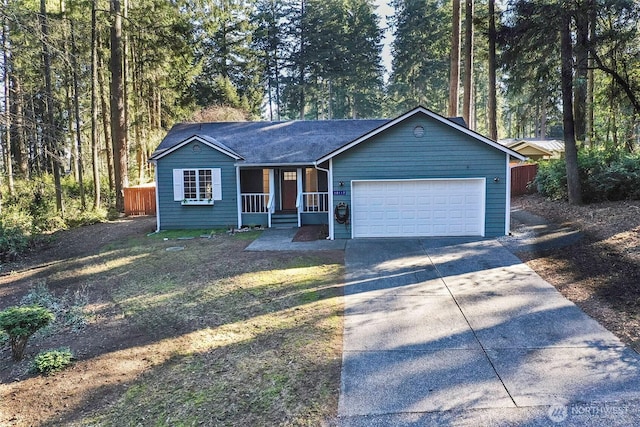 single story home with an attached garage, driveway, and a wooded view