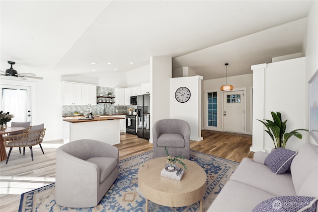 living area featuring lofted ceiling, recessed lighting, light wood-style floors, a ceiling fan, and baseboards