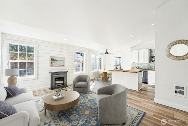 living area featuring a fireplace, lofted ceiling, recessed lighting, light wood-style floors, and baseboards