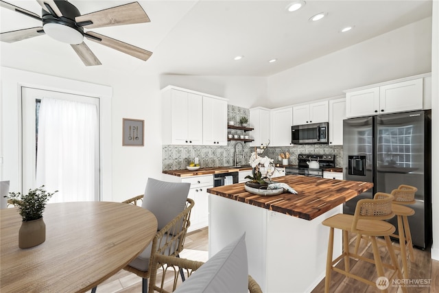 kitchen featuring appliances with stainless steel finishes, white cabinetry, wood counters, and tasteful backsplash