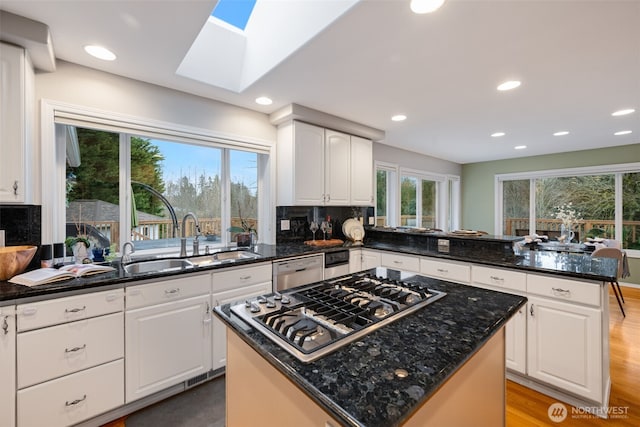 kitchen with a kitchen island, sink, white cabinets, and appliances with stainless steel finishes