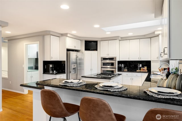 kitchen with tasteful backsplash, sink, a breakfast bar area, light hardwood / wood-style floors, and stainless steel appliances