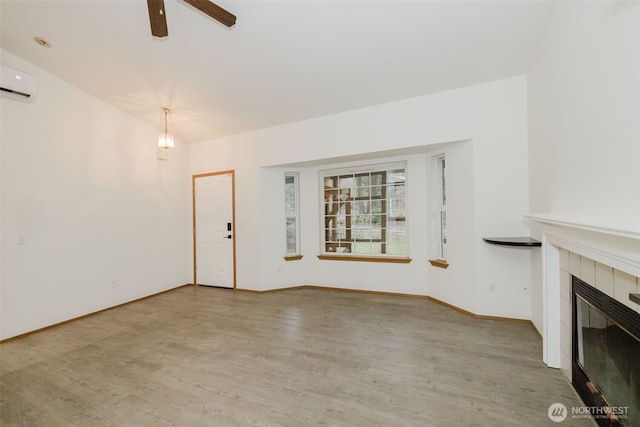 unfurnished living room featuring vaulted ceiling, an AC wall unit, hardwood / wood-style flooring, ceiling fan, and a fireplace