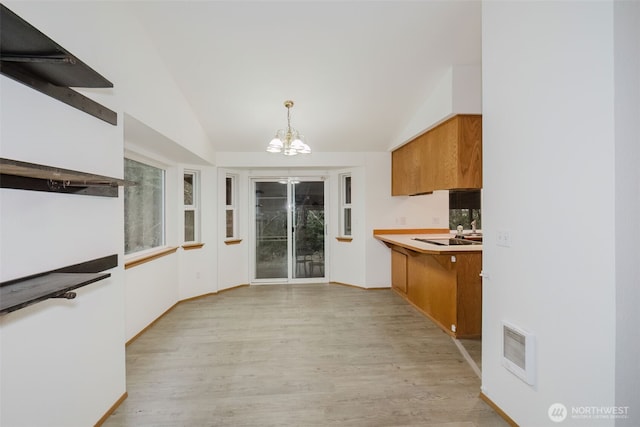 kitchen with pendant lighting, vaulted ceiling, a chandelier, and light hardwood / wood-style flooring