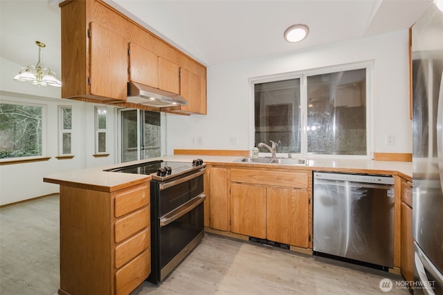 kitchen with sink, hanging light fixtures, light wood-type flooring, appliances with stainless steel finishes, and kitchen peninsula