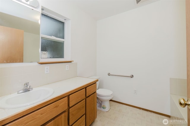 bathroom with vanity, backsplash, and toilet