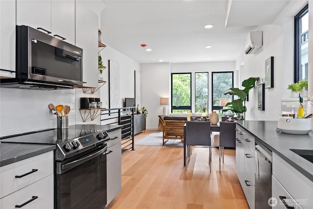 kitchen featuring an AC wall unit, white cabinetry, dishwasher, backsplash, and electric range