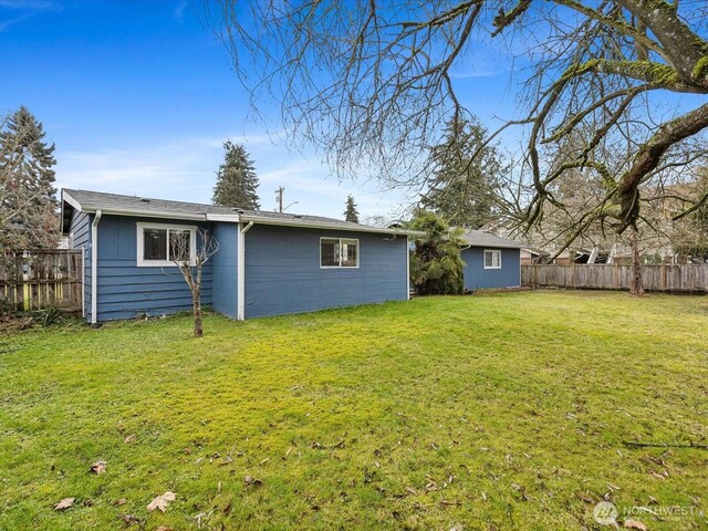 back of property with fence and a yard