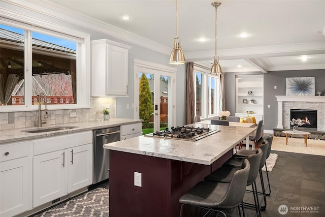 kitchen with light stone counters, hanging light fixtures, appliances with stainless steel finishes, open floor plan, and white cabinets