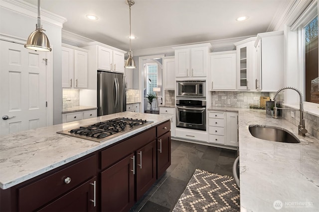 kitchen featuring appliances with stainless steel finishes, pendant lighting, glass insert cabinets, and a sink