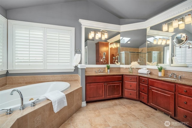 full bathroom featuring double vanity, lofted ceiling, a stall shower, a sink, and a bath