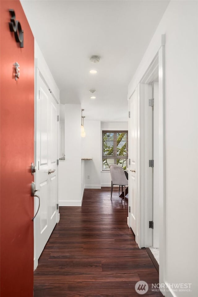 hall with dark wood-style flooring and baseboards