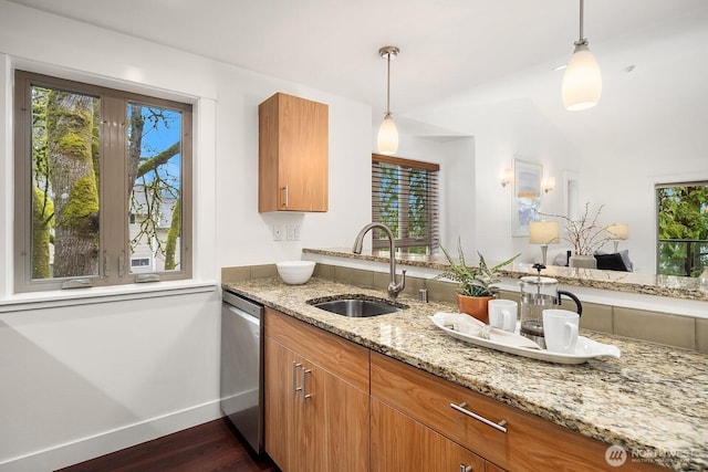 kitchen featuring dishwasher, dark wood-style flooring, hanging light fixtures, light stone countertops, and a sink