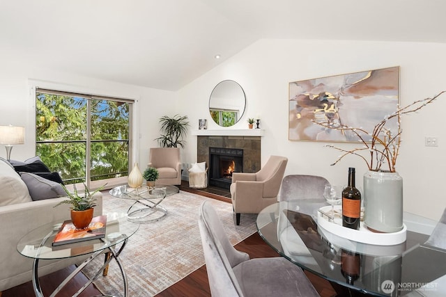 living room with vaulted ceiling, a fireplace, and wood finished floors