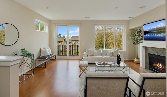 living area with a premium fireplace, wood finished floors, and baseboards