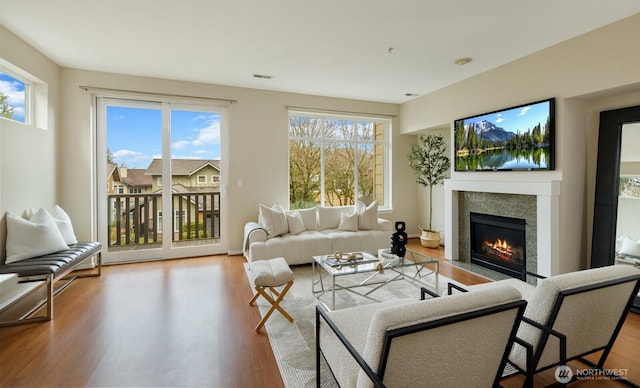 living area with a fireplace with flush hearth, visible vents, and wood finished floors