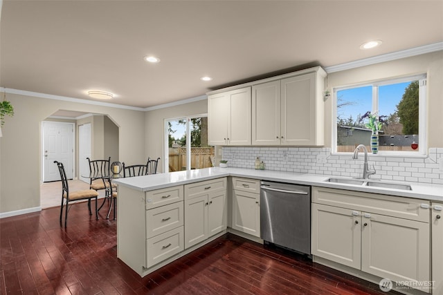 kitchen with a sink, stainless steel dishwasher, a peninsula, crown molding, and light countertops