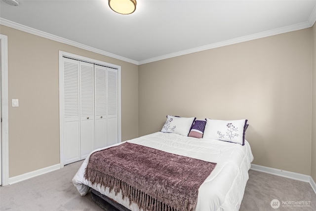 bedroom with a closet, carpet flooring, crown molding, and baseboards