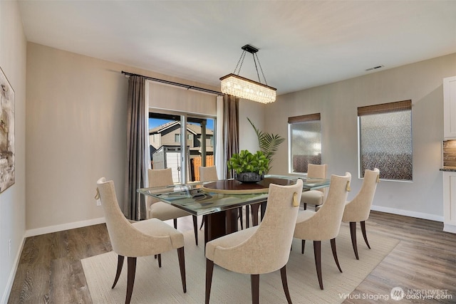 dining space featuring light wood-type flooring, visible vents, and baseboards