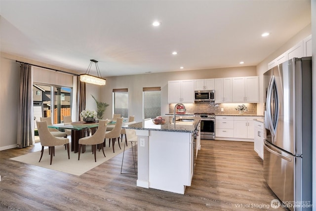 kitchen featuring a sink, appliances with stainless steel finishes, stone countertops, and wood finished floors