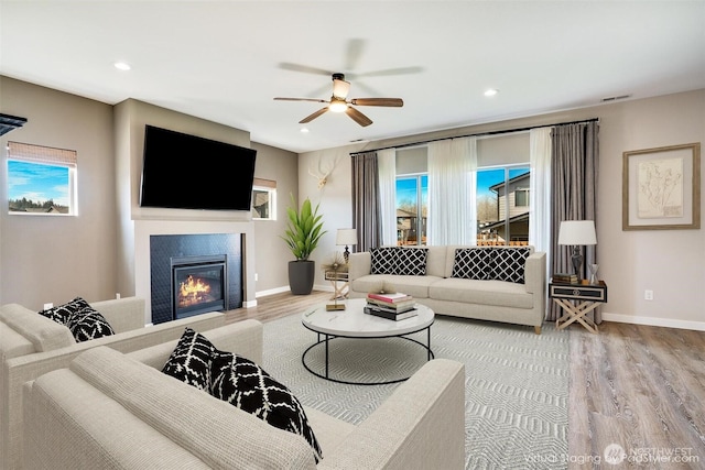 living area with a glass covered fireplace, baseboards, and wood finished floors