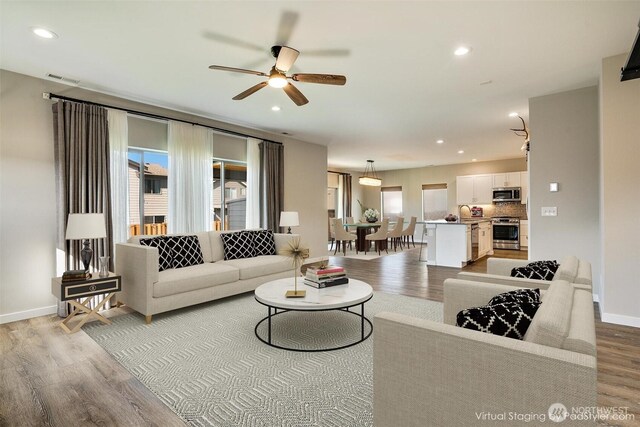 living area featuring visible vents, a ceiling fan, wood finished floors, recessed lighting, and baseboards