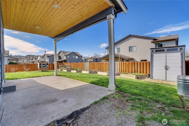 view of yard with a residential view, a shed, a fenced backyard, an outbuilding, and a patio