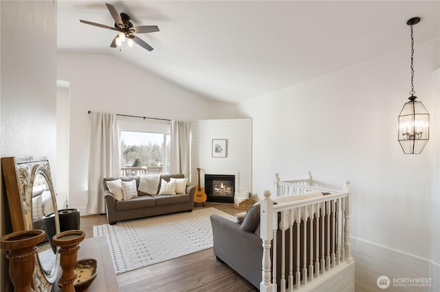 living room featuring hardwood / wood-style floors, vaulted ceiling, and ceiling fan with notable chandelier