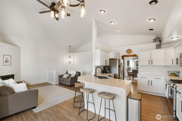 kitchen with stainless steel appliances, vaulted ceiling, pendant lighting, sink, and white cabinetry