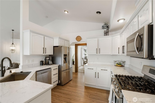 kitchen with sink, stainless steel appliances, white cabinets, hanging light fixtures, and light stone countertops