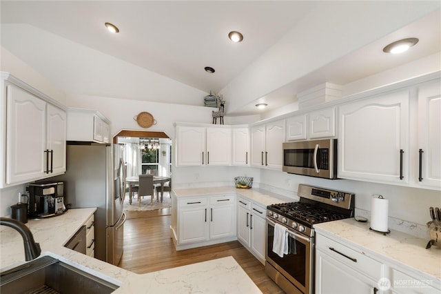 kitchen with sink, stainless steel appliances, white cabinetry, and light stone counters