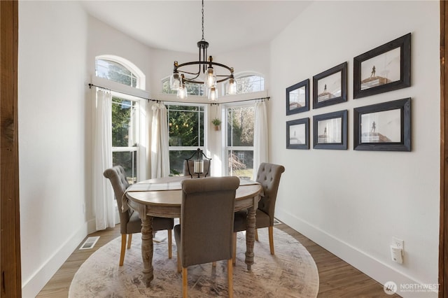 dining room with hardwood / wood-style floors and an inviting chandelier