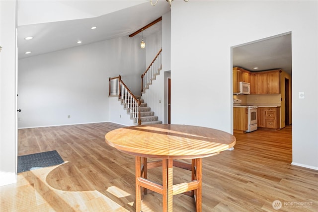 dining area featuring high vaulted ceiling and light hardwood / wood-style flooring