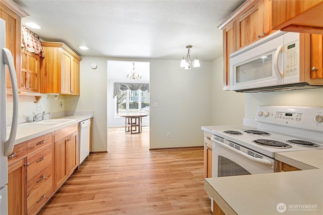 kitchen with sink, white appliances, light hardwood / wood-style flooring, a notable chandelier, and decorative light fixtures