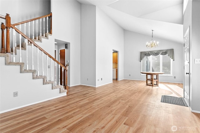 unfurnished living room with an inviting chandelier, high vaulted ceiling, and light wood-type flooring