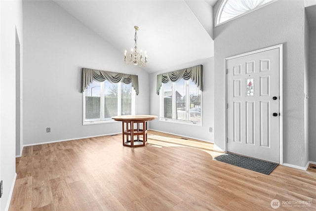 entryway featuring an inviting chandelier, high vaulted ceiling, and light wood-type flooring